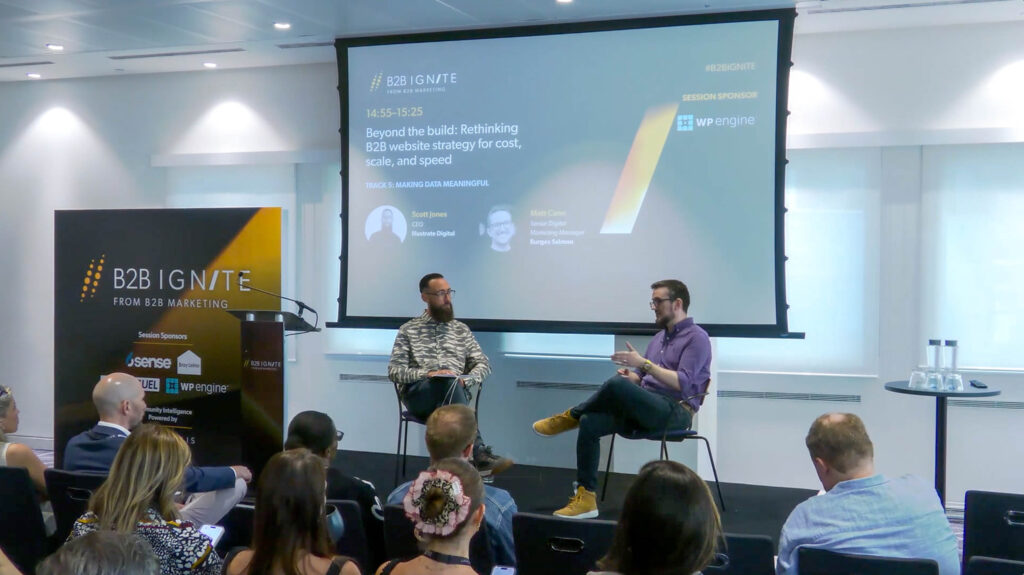 Scott Jones of Illustrate Digital and Matt Cann of Burges Salmon presenting at a B2B Ignite marketing event in a modern conference room with an audience seated in rows. A large projection screen displays presentation slides in the background.